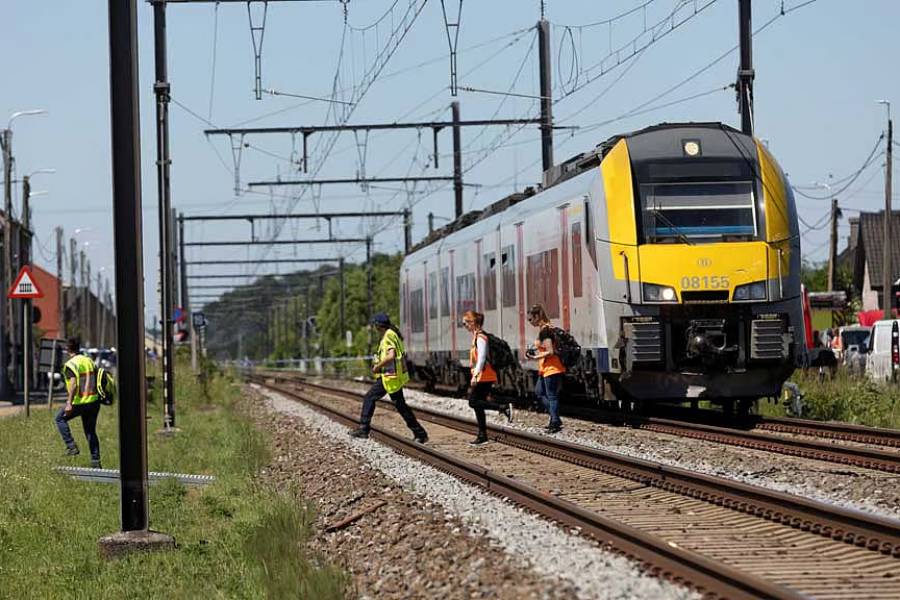 Emergency personnel walk near the scene where a school bus was struck by a train at a level crossing leading to multiple casualities, near the town of Buggenhout, Belgium, May 26, 2026.
