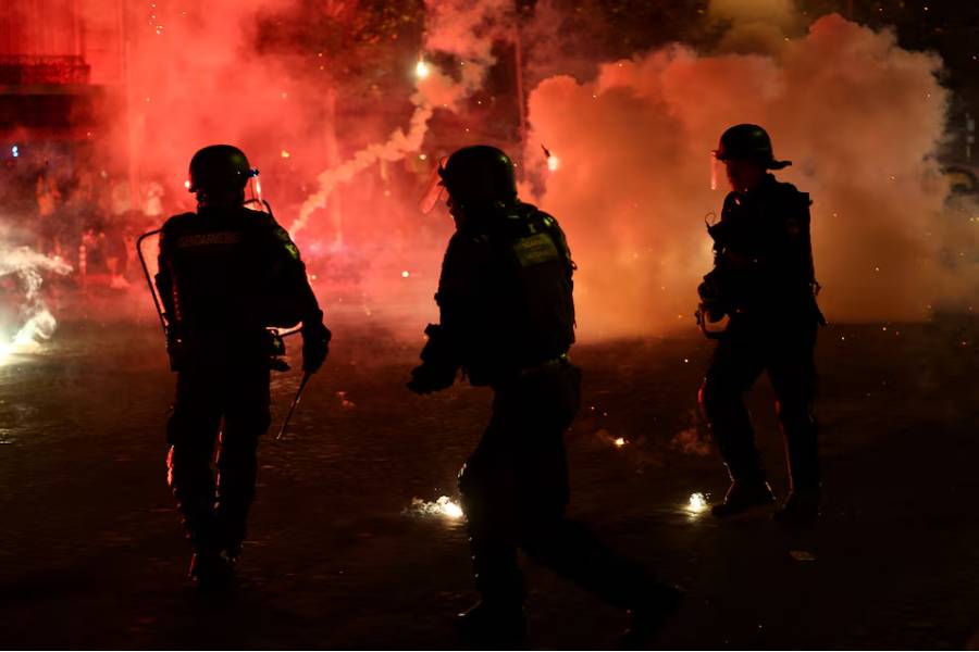Soccer Football - UEFA Champions League - Paris St Germain fans celebrate winning the UEFA Champions League - Paris, France - May 31, 2026 Police officers protect themselves from flares after Paris St Germain won the UEFA Champions League REUTERS/Abdul Saboor