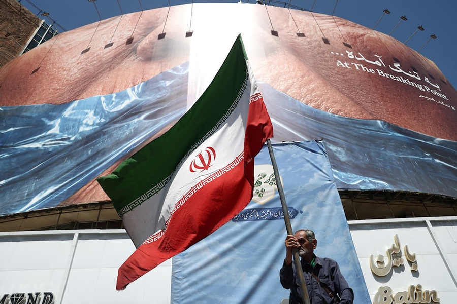 A man holds an Iranian flag near an anti-US billboard depicting U.S. President Donald Trump and the Strait of Hormuz, in Tehran, Iran, on May 30, 2026 — WANA (West Asia News Agency) via REUTERS