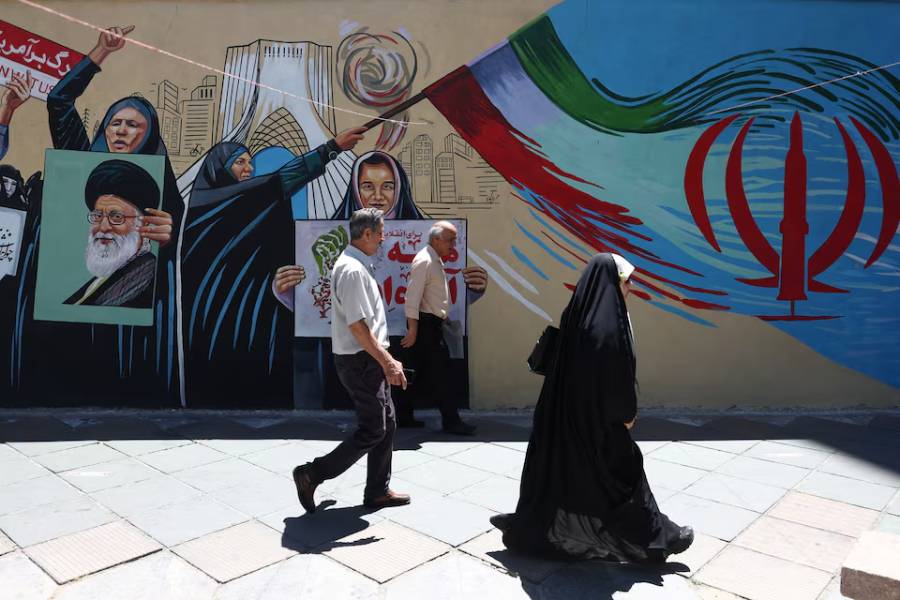 People walk on a street near a mural featuring an image of the late Supreme Leader of Iran, Ayatollah Ali Khamenei, in Tehran, Iran, June 1, 2026.