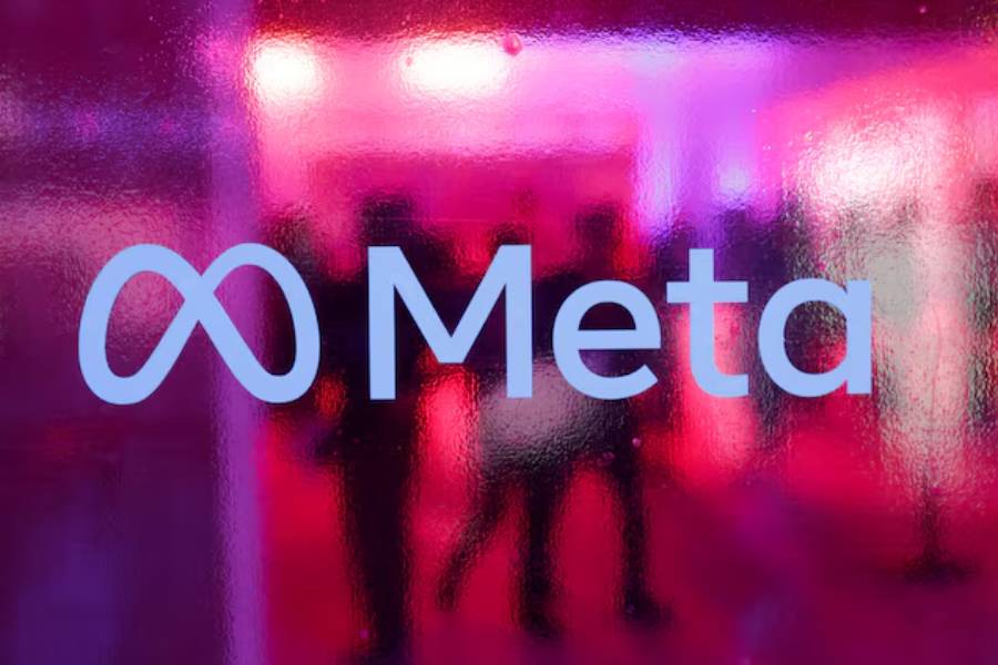 People walk behind a logo of Meta Platforms company, during a conference in Mumbai, India, September 20, 2023.