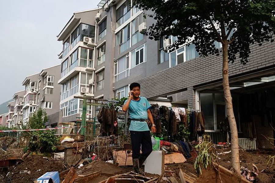 A local resident surnamed Gao, 60, talks on his phone as he stands on debris at his damaged house, after remnants of Typhoon Doksuri brought rains and floods in Mentougou district, Beijing, China, Aug 4, 2023.