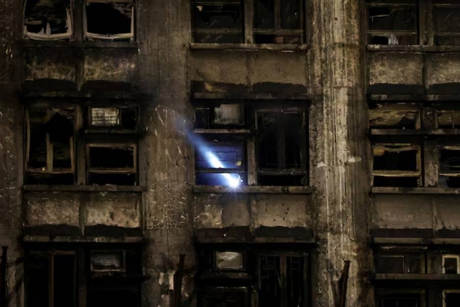 A rescuer works inside a damaged building at the scene after a deadly fire at the Wang Fuk Court housing complex in Hong Kong, China November 27, 2025.