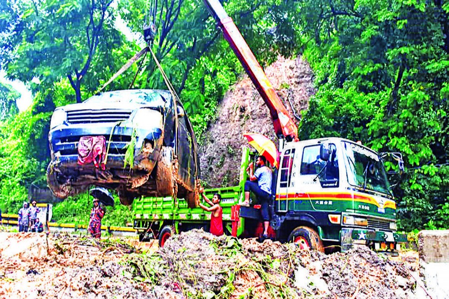 A vehicle trapped in mud that fell during a landslide is being pulled out by a crane — FE photo