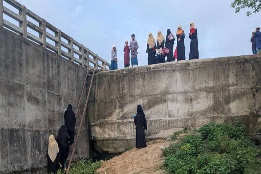 Photo shows locals crossing a bridge over the Eidgaon Canal in Cox's Bazar by climbing a ladder, risking their lives - FE Photo