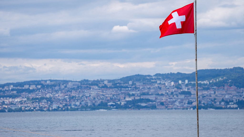 A Swiss flag is pictured in front of the Swiss city of Lausanne ahead of a Jun 14 vote on a proposal from the right-wing Swiss People's Party to cap the population at 10 million inhabitants by 2050, in Evian-les-Bains, France, Jun 12, 2026. REUTERS/Denis Baliboouse