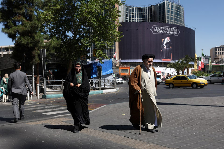 People walk past a billboard with a picture of the late Iran's Supreme Leader Ayatollah Ali Khamenei, after US and Iranian officials said they had reached a deal to end their war and reopen the Strait of Hormuz, in Tehran, Iran, on June 15, 2026 — WANA (West Asia News Agency) via REUTERS