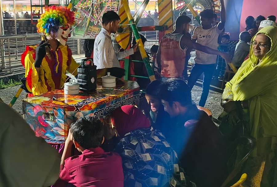 Visitors at a local fair crowd around a traditional Bioscope.