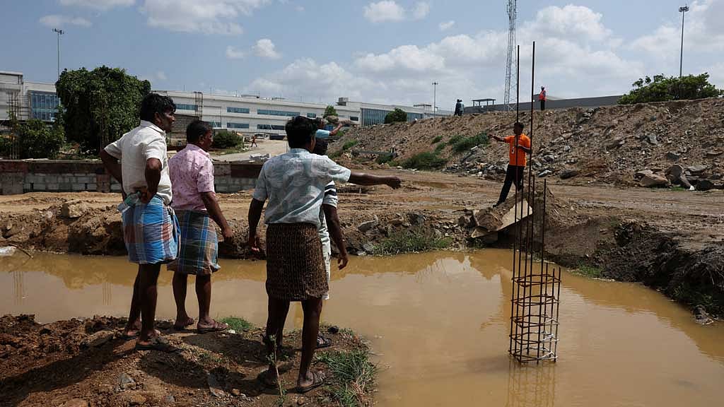 Farmers speak with a security guard near the compound wall of a Tata Electronics' components factory for Apple’s iPhone, in Hosur, Tamil Nadu, India Jun 15, 2026. REUTERS/Priyanshu Singh