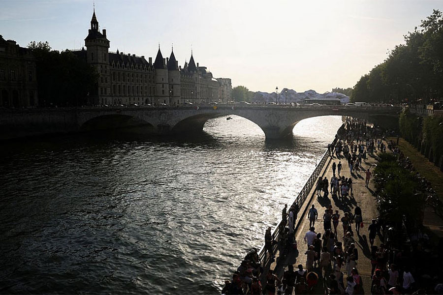 People walk along the banks of the Seine River in Paris, France, during a heatwave.