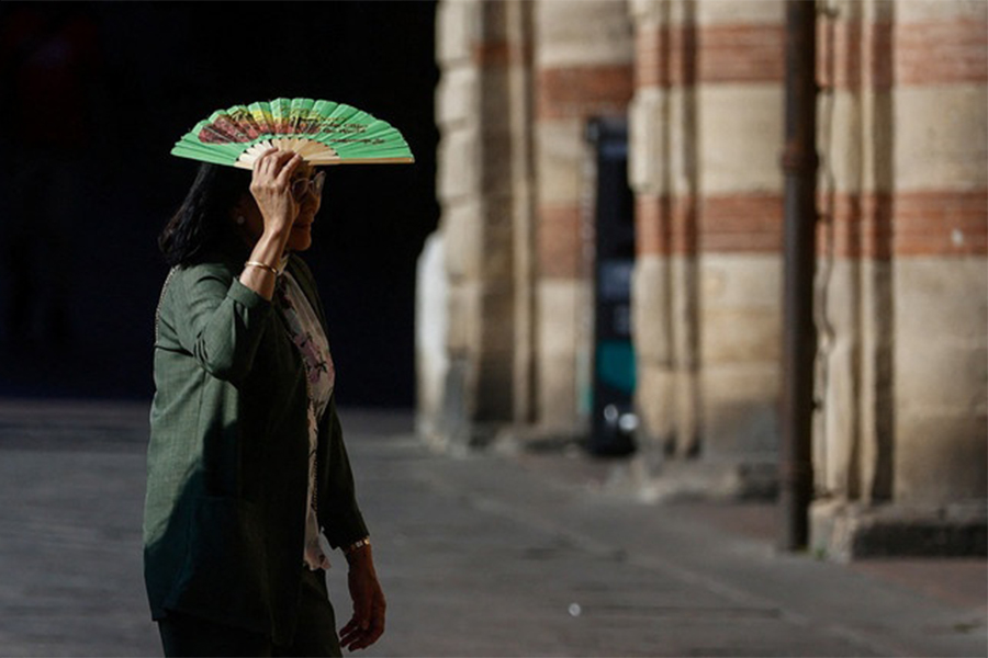A woman holds a fan over her face to shield herself from the sun during hot weather in Bologna, Italy, on June 20, 2026 — Reuters photo