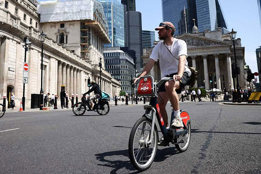 A man cycles past the Bank of England as Britain experiences record temperatures disrupting schools and transport networks in London, Britain, June 23, 2026.