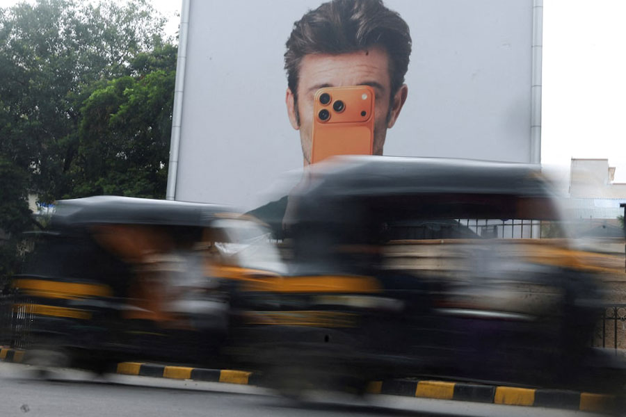 Auto rickshaws move past an Apple iPhone hoarding on a street in Mumbai, India, June 29, 2026.