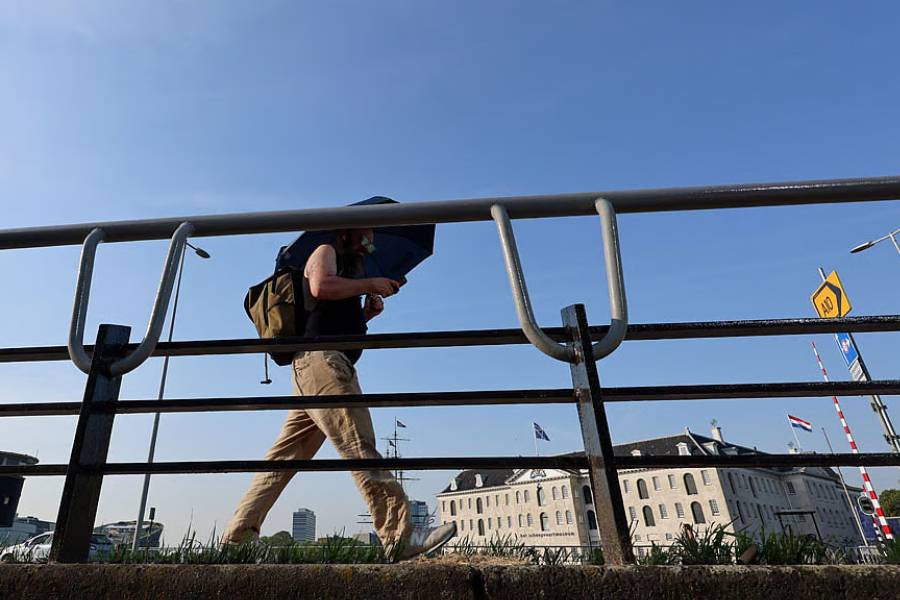 A man walks with an umbrella in Amsterdam, during the heatwave hitting the country, while a code red alert is issued, in Amsterdam, the Netherlands, Jun 26, 2026.