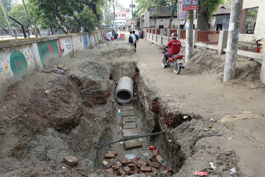 Photo shows a partially installed RCC drainage pipe in an excavated section of the road beside Manikganj Government High School where construction delays have left thousands of commuters facing safety risks - FE Photo