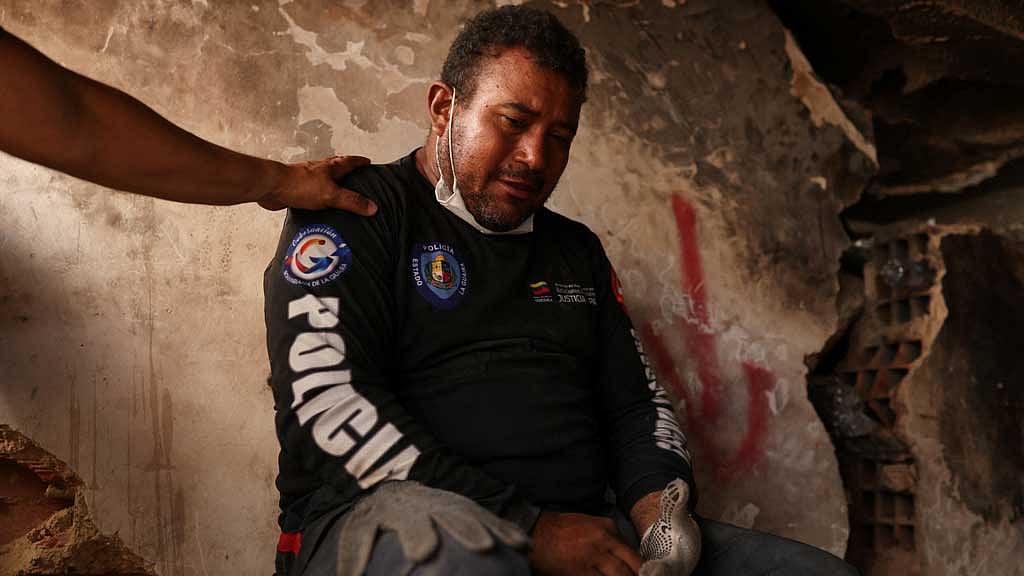 Jimmy Gamboa is comforted by a friend as rescuers search for the bodies of his wife and 16-year-old son, in the aftermath of the Jun 24 earthquakes in La Guaira, Venezuela, Jul 8, 2026. REUTERS/Pablo Sanhueza