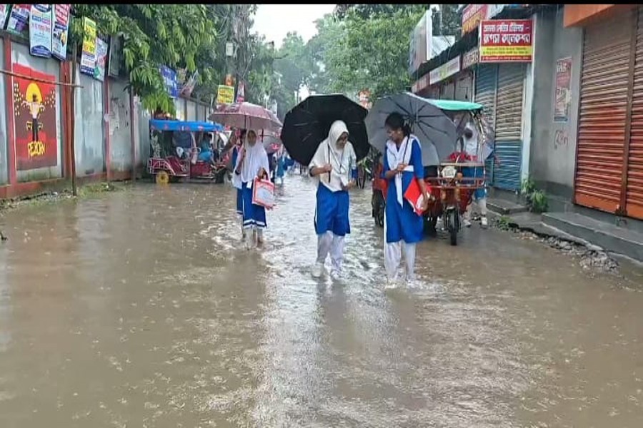 After two days' incessant rainfall, students wade through knee-deep water on their way to school at Munshi Para in Gaibandha town — FE Photo