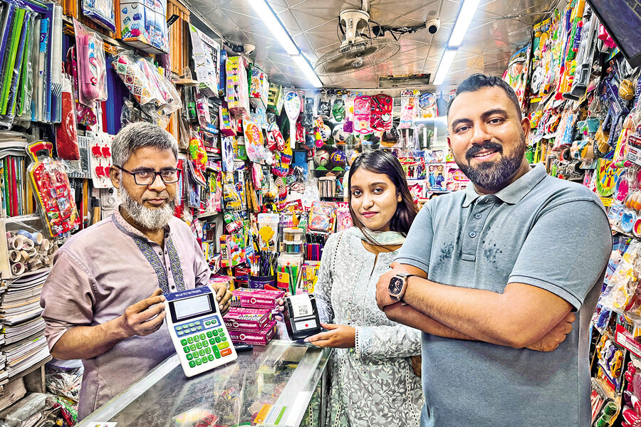 Co-founder of Zatiq, Mumtahina Anika (middle) holds Zatiq's Receipt Printer Product and a retailer (left) shows Zatiq's Business Calculator Product while the founder of Zatiq, Sultan Moni looks on.