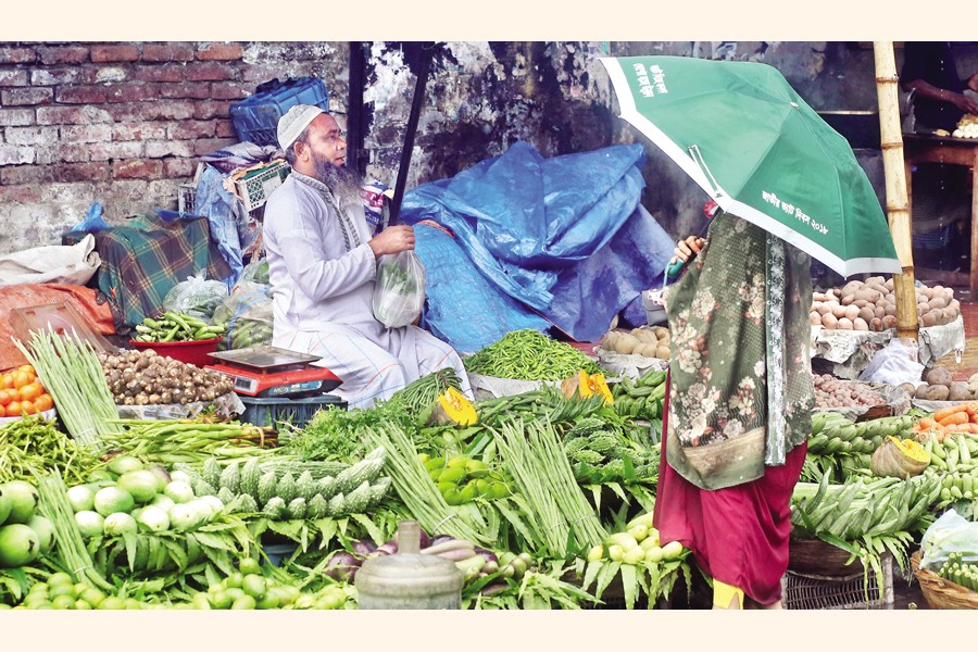 A vendor sells vegetables in Shantinagar area of Dhaka city on Friday. Torrential rain the city has been experiencing for the last several days has pushed up prices of vegetables. — FE photo