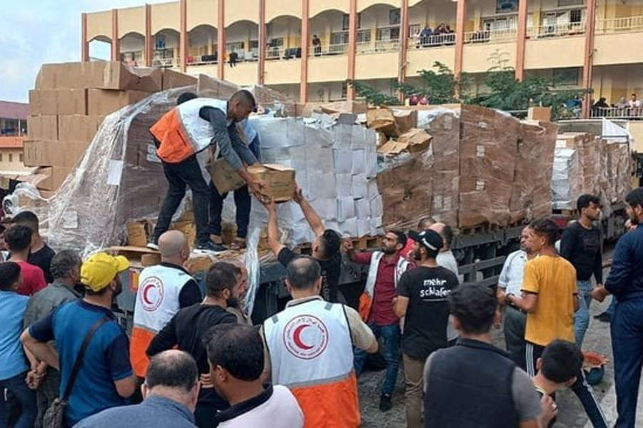 Members of the Palestine Red Crescent Society distribute aid to people in Deir al-Balah, in the central Gaza Strip, in this handout picture released on October 25, 2023.