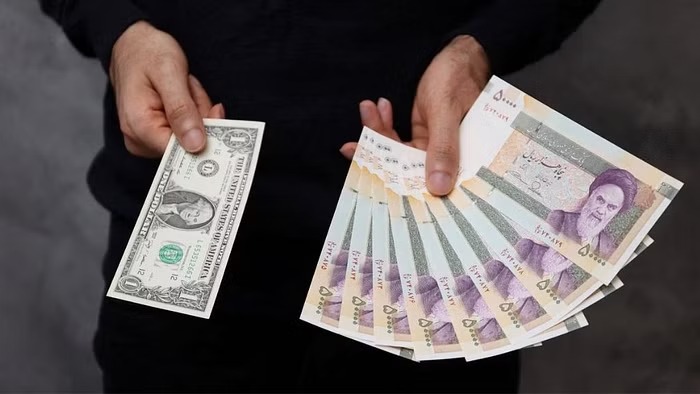 A currency dealer poses for a photo with a US one dollar bill and the amount being given when converting it into Iranian rials in an exchange shop in Tehran, Iran Dec 25, 2022. Majid Asgaripour/WANA (West Asia News Agency) via REUTERS
