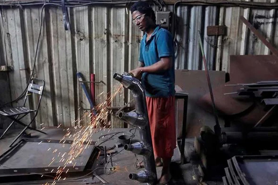 A worker grinds a steel pipe to be used in air ducts inside a workshop at an industrial area in Mumbai, India, May 31, 2018. REUTERS
