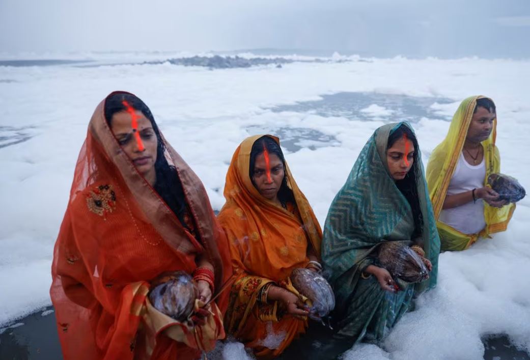 Hindu devotees worship the Sun god as they stand amidst the foam covering the polluted Yamuna river during the Hindu religious festival of Chhath Puja on a smoggy morning in New Delhi, India, November 20, 2023. REUTERS/Anushree Fadnavis