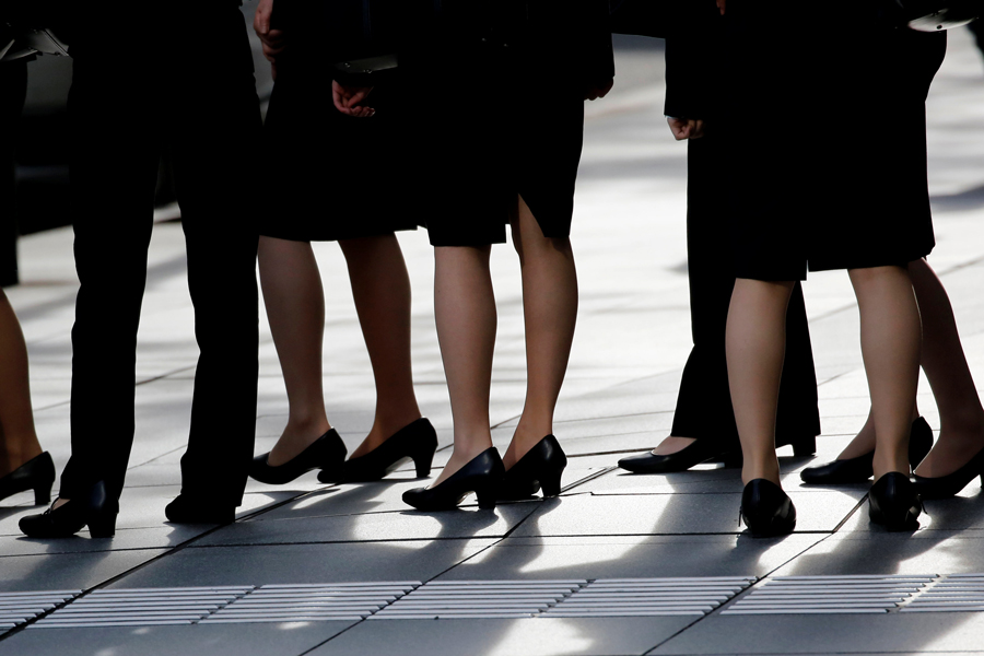 Female office workers wearing high heels, clothes and bags of the same colour are seen at a business district in Tokyo, Japan, June 4, 2019.