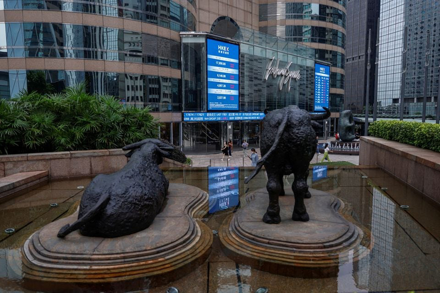 Bull statues are placed in font of screens showing the Hang Seng stock index and stock prices outside Exchange Square, in Hong Kong, China, August 18, 2023.