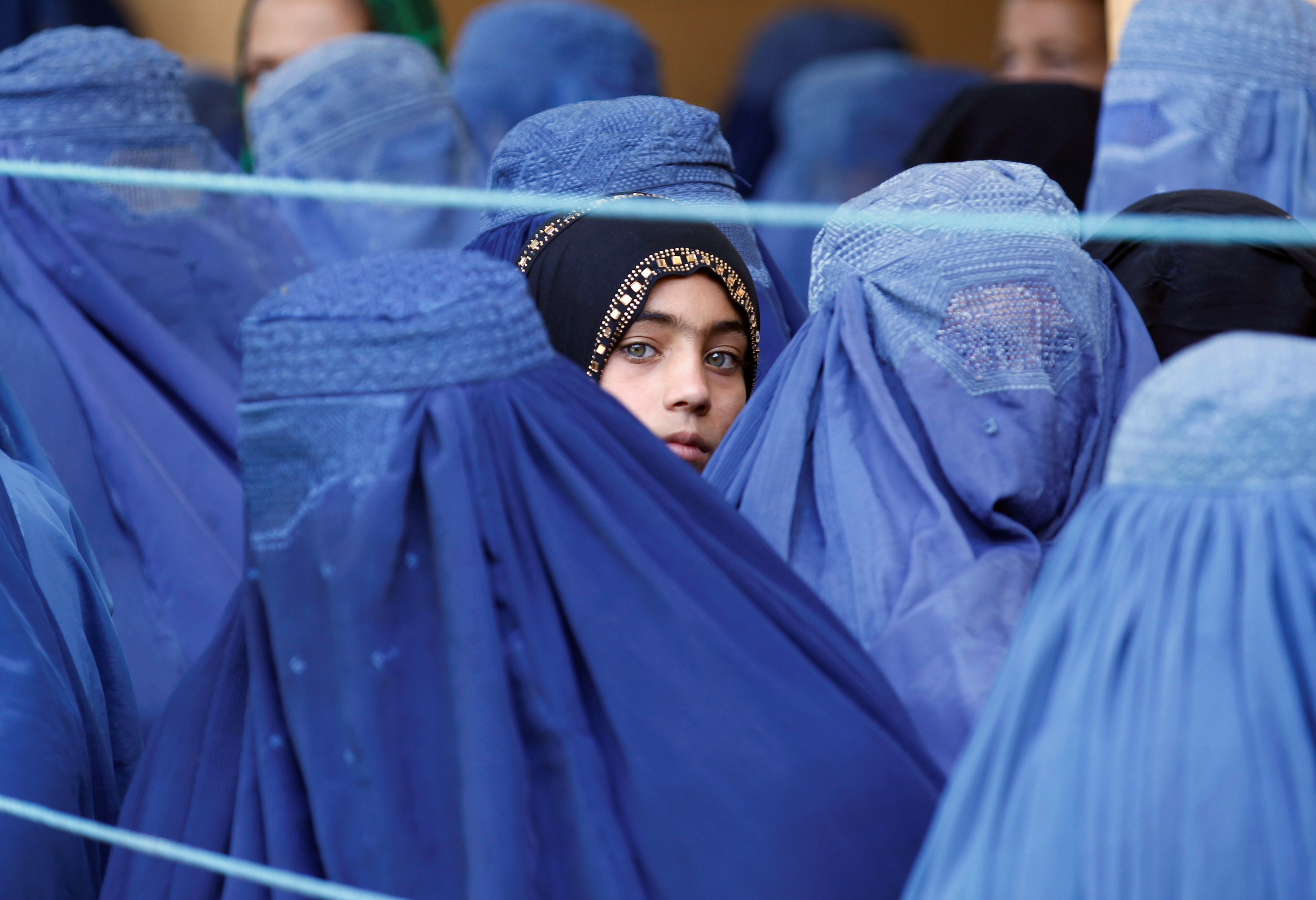 A girl looks on among Afghan women lining up to receive relief assistance, during the holy month of Ramadan in Jalalabad, Afghanistan, June 11, 2017. REUTERS/Parwiz