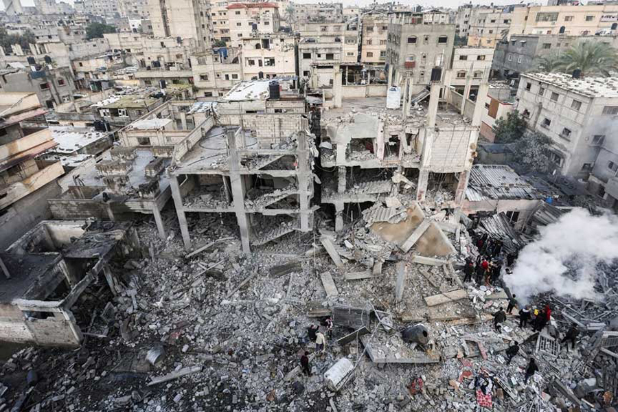 Palestinians gather as smoke rises at the site of Israeli strikes on houses in Khan Younis, in the southern Gaza Strip December 14, 2023.