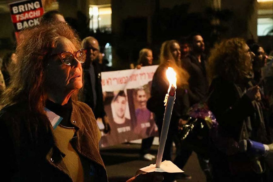 A woman holds a candle as people protest following an announcement by Israel's military that they had mistakenly killed three Israeli hostages being held in Gaza by Palestinian Islamist group Hamas, at a demonstration in Tel Aviv, Israel, December 15, 2023.