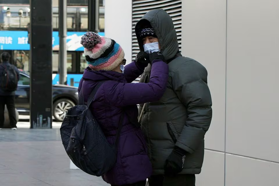 A woman adjusts the hood on a down jacket for a man on a cold winter day in Shanghai, China on December 21, 2023 — Reuters photo