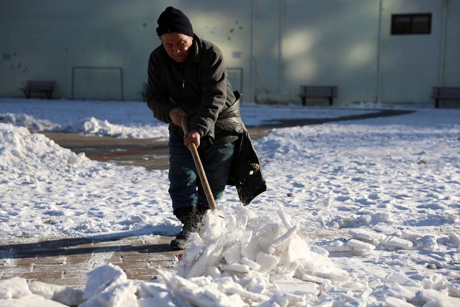 A worker clears snow at a park during winter solstice in Beijing, China December 22, 2023.