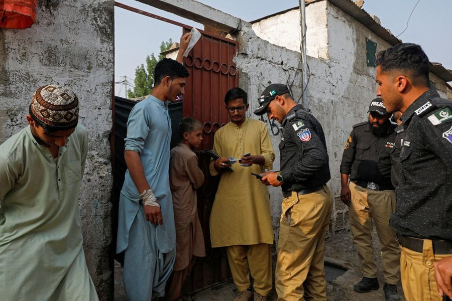 Police officers, along with workers from the National Database and Registration Authority (NADRA), check the identity cards of Afghan citizens during a door-to-door search and verification drive for undocumented Afghan nationals, in an Afghan Camp on the outskirts of Karachi, Pakistan, November 21, 2023.