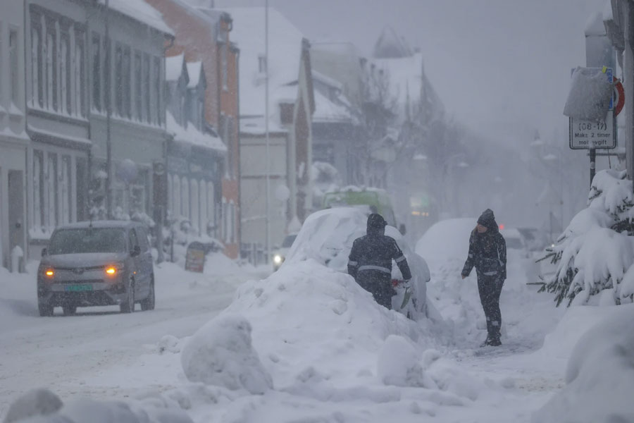 People attempt to clear the snow off a vehicle, in Kristiansand, Norway, Tuesday, Jan. 2, 2024. Finland and Sweden have recorded this winter’s cold records on Tuesday as a temperatures plummeted to over minus 40 degrees as a result of a cold spell prevailing in the Nordic region.