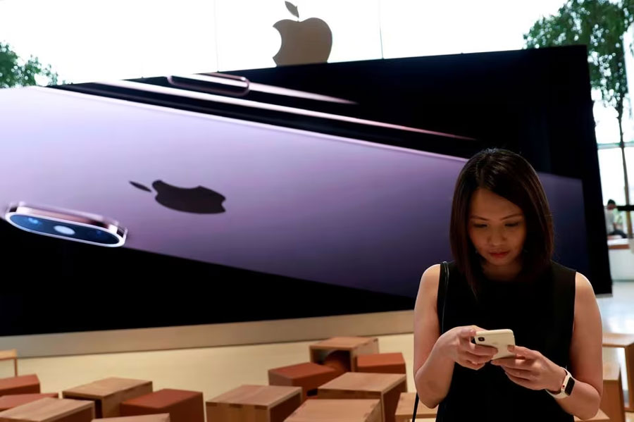 A woman checks her phone at a flagship Apple store at Iconsiam shopping mall in Bangkok, Thailand November 9, 2018. REUTERS/Soe Zeya Tun/File Photo Acquire Licensing Rights