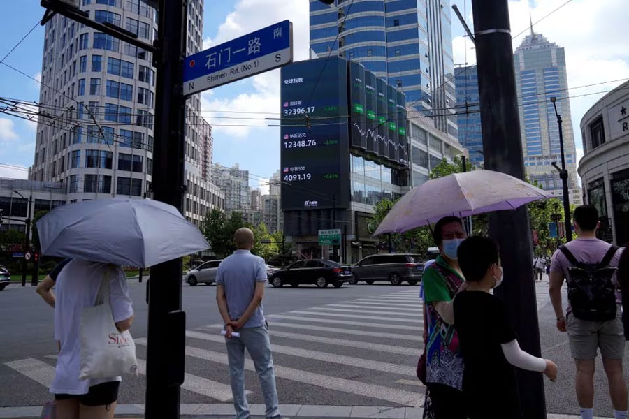 Pedestrians wait to cross a road at a junction near a giant display of stock indexes in Shanghai, China August 3, 2022. REUTERS/Aly Song/File Photo Acquire Licensing Rights