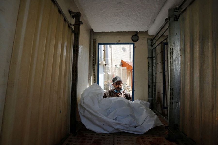 A man man works on moving the body of a Palestinian, who was killed in Israeli strikes, from an ice cream truck where it was kept, as the hospital morgues are packed, amid the ongoing Israeli-Palestinian conflict, in the central Gaza Strip on October 15, 2023 — Photo via Reuters/Files