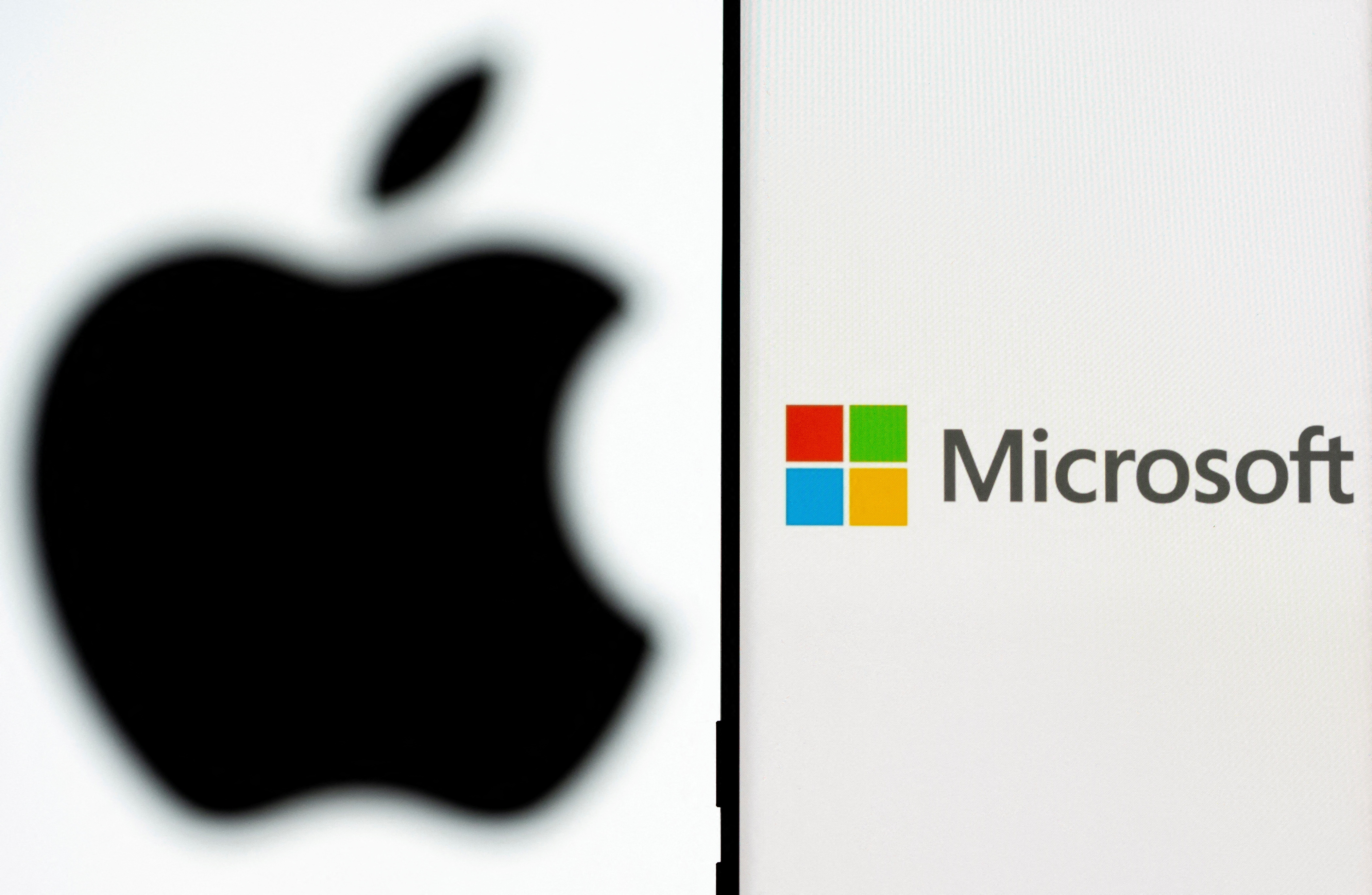 Microsoft logo is seen on the smartphone in front of displayed Apple logo in this illustration taken, July 26, 2021. REUTERS