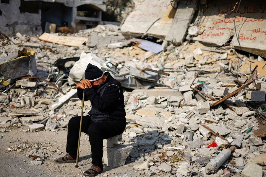 Ziad Mansour, a neighbour of the Abu Aweidah family, sits next to writing painted on a wall amid the rubble of the family's house, which was destroyed in a deadly Israeli strike amid the ongoing conflict between Israel and the Palestinian Islamist group Hamas, in Rafah, Gaza Strip, January 9, 2024. REUTERS/Mohammed Salem Acquire Licensing Rights