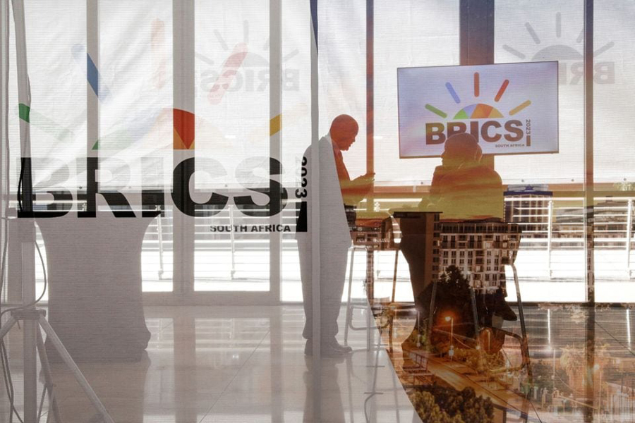 Delegates interact next to the logos of the BRICS summit during the 2023 BRICS Summit at the Sandton Convention Centre in Johannesburg, South Africa on August 23, 2023.