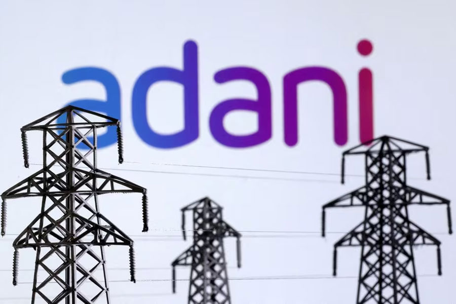 Electric power transmission pylon miniatures and Adani Green Energy logo are seen in this illustration taken, December 9, 2022.