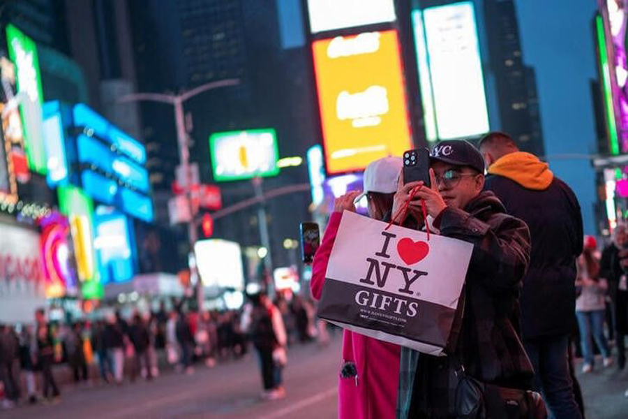 A man takes a picture while carrying a shopping bag in Times Square, New York, US, December 25, 2023.