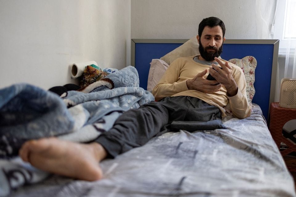 Abdulalim Muaini lies in bed looking at pictures of his children and wife who died next to him in the earthquake one year ago, contemplating how it shattered the new life they had built in southern Turkey after having fled war in Syria, in Bursa, Turkey on January 4, 2024 — Reuters photo