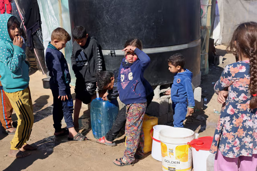 Displaced Palestinian children, who fled their houses due to Israeli strikes, wait to collect water amid shortages, at a tent camp in Rafah in the southern Gaza Strip February 1, 2024.