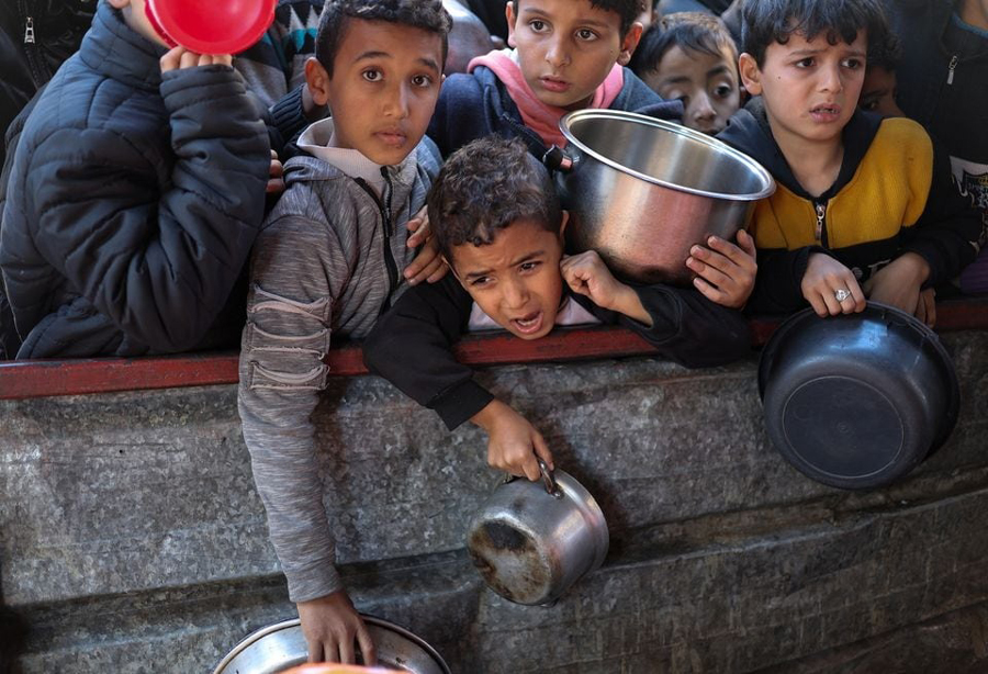 Palestinian children wait to receive food cooked by a charity kitchen amid shortages of food supplies, as the ongoing conflict between Israel and the Palestinian Islamist group Hamas continues, in Rafah, in the southern Gaza Strip, February 5, 2024.