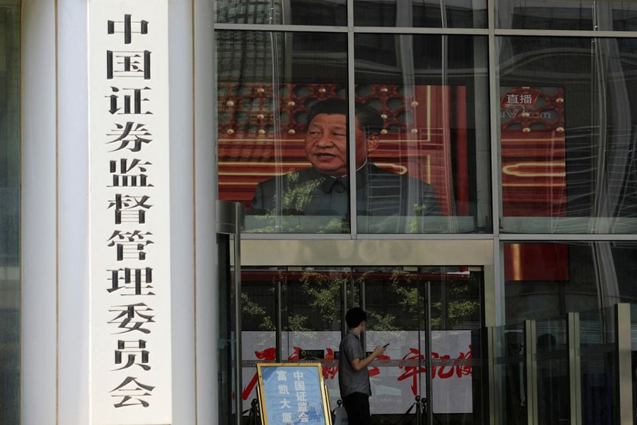 A man stands near a screen showing news footage of Chinese President Xi Jinping at the China Securities Regulatory Commission (CSRC) building on the Financial Street in Beijing, China July 9, 2021.