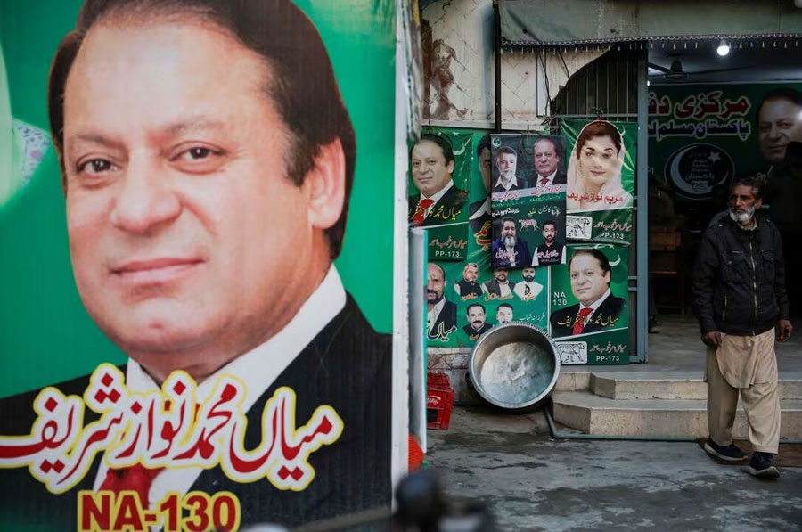 A man stands near the banner and campaign posters of Pakistan's former Prime Minister Nawaz Sharif ahead of the general elections, in Lahore, Pakistan, February 5, 2024.