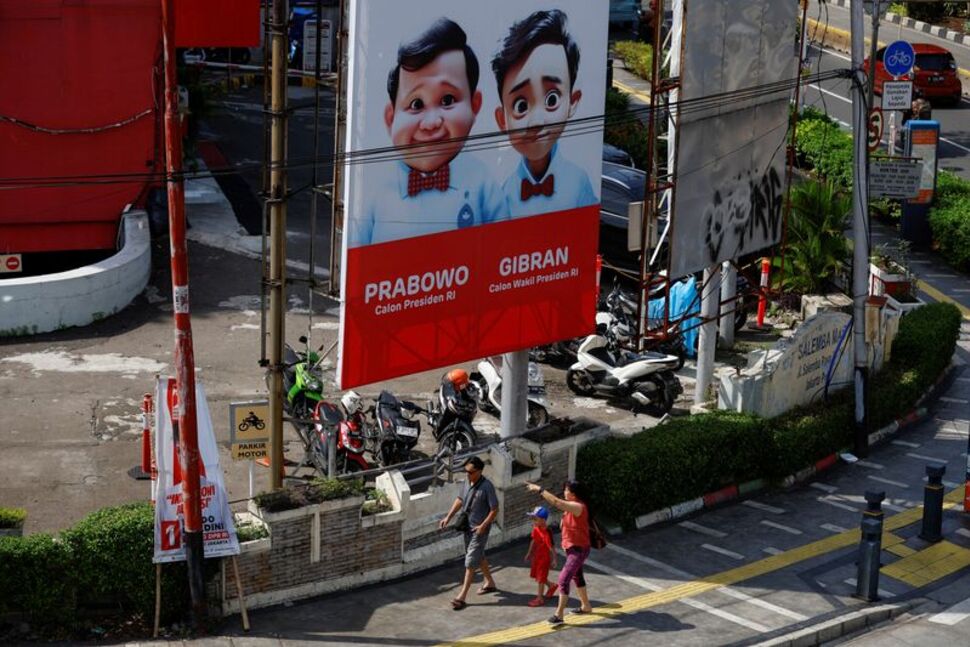 People walk past a billboard promoting Indonesia's Defence Minister and Presidential candidate Prabowo Subianto and his running mate Gibran Rakabuming Raka, who is the eldest son of Indonesian President Joko Widodo and current Surakarta's Mayor, ahead of the upcoming general election in Jakarta, Indonesia, January 12, 2024. REUTERS/Willy Kurniawan/File Photo